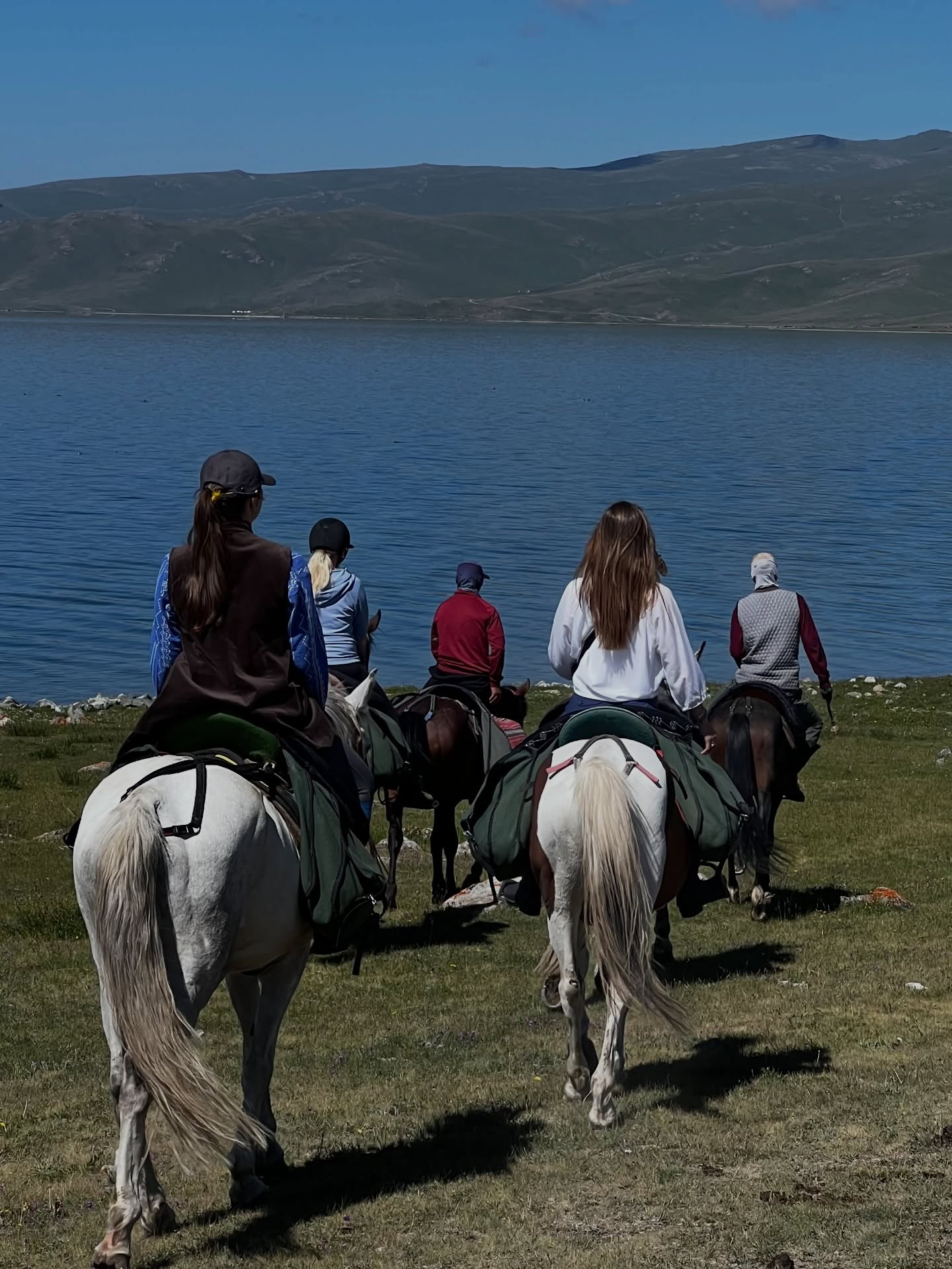 A small group of riders at the shore of Song-Kol lake