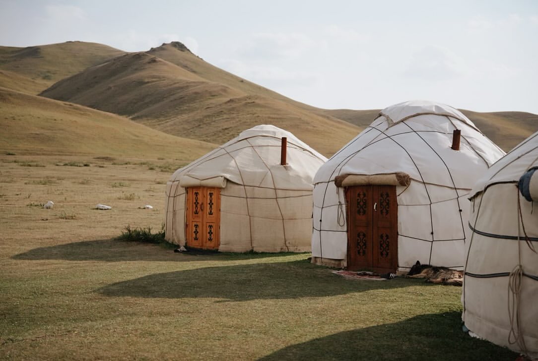 Yurts with carved wooden doors at a camp in the Naryn region